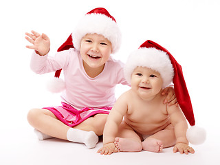 Image showing Two children wearing red Christmas caps and smile