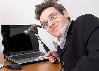 Image showing Businessman in spectacles gone mad with a hammer