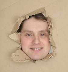 Image showing Male face look up through hole carton