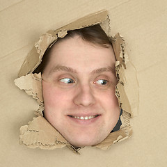 Image showing Male face look up from hole in carton