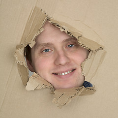 Image showing Male face look up from hole in carton 