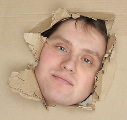 Image showing Male face look up from hole in carton 