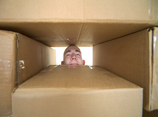 Image showing Face looking trough window in pile cardboard boxes