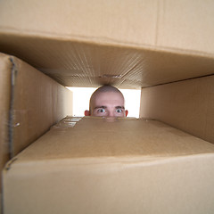 Image showing Face looking trough window in pile cardboards