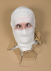 Image showing Male face on bandage in carton hole