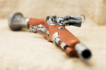 Image showing Ancient pistol on background canvas