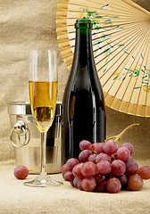 Image showing Champagne bottle, bucket, goblet and grapes