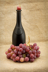 Image showing Dark bottle and red grapes bunch