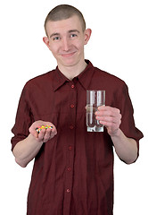 Image showing Young man with glass of water and tablets