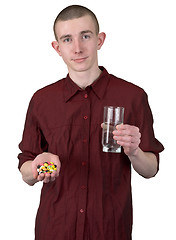 Image showing Young man with glass of water and tablets