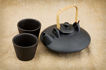 Image showing Black ceramic chinese teapot and mugs