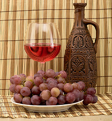 Image showing Carafe, grape and goblet on mat