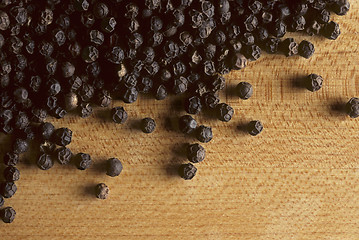 Image showing Whole black peppercorns on butcherblock