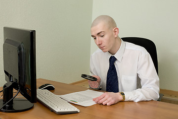 Image showing Businessman with a magnifier on a workplace