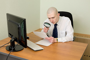 Image showing Businessman with a magnifier on a workplace