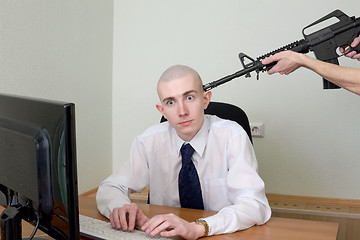 Image showing Man at office with a rifle near a head