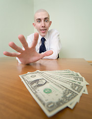 Image showing Man reaches for a batch of money