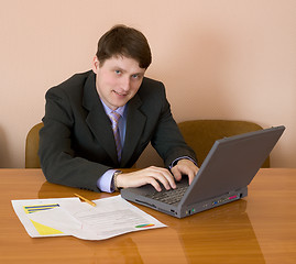 Image showing Businessman sits at table with the laptop
