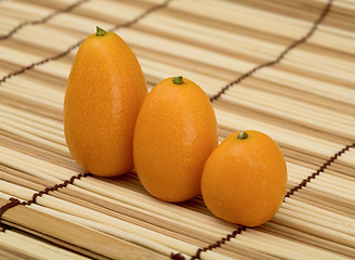 Image showing Three fresh kumquat against a mat