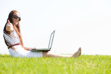 Image showing young feamle sit in the park and using a laptop
