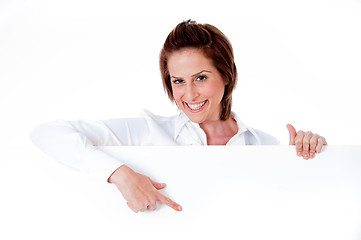 Image showing Happy young female holding a blank billboard, pointing at it