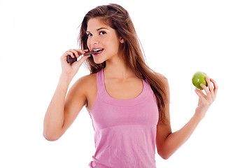 Image showing sexy girl biting a chocklate and keep the apple in other hand