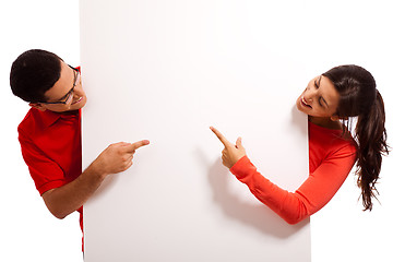 Image showing Playful young couple pointing the blank white baord