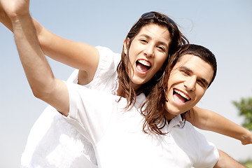 Image showing Smiling young couple holding hands eachother while piggyback