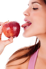 Image showing closeup of young girl tasting the apple by her tounge