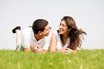 Image showing young couple smiling by laying down in a green grass field