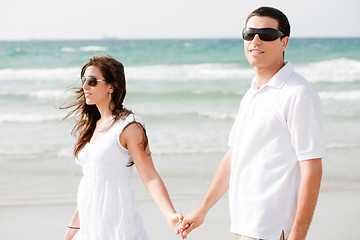 Image showing Young couple holding hands and walking by the beach