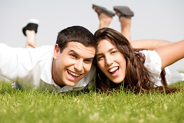 Image showing Playful young couple laying down in a green grass field