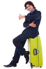 Image showing Corporate man sitting above the luggage showing thumbsup