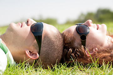 Image showing Happy couple laying on a lawn and looks