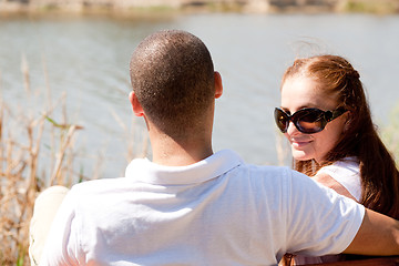 Image showing Rear view of young couple sitting at the lake side