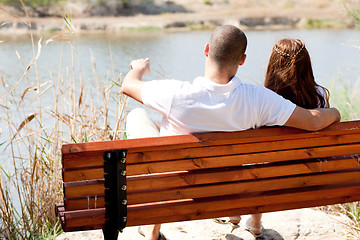 Image showing young couple seated at the wooden bench