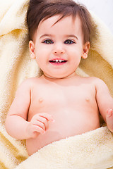 Image showing Cute baby smiling covered in yellow towel