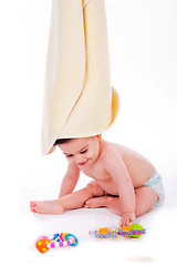 Image showing Baby with towel on is head while playing toys