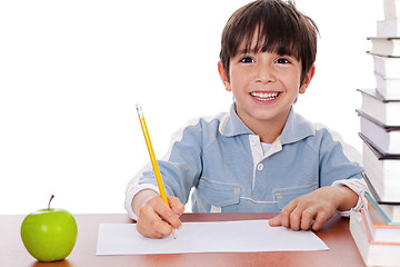 Image showing School boy doing his homework with an apple beside him