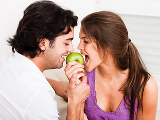 Image showing closeup of young couple biting green apple