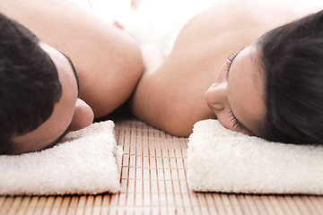 Image showing Young man and woman lying on towel to take spa