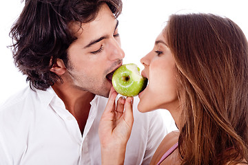 Image showing young couple playfully biting green apple