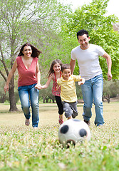 Image showing Parents and two young children playing soccer in the green field