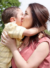 Image showing Children kissing his mom in a park