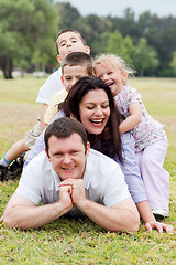 Image showing Happy family piled up  on the park and looking at you