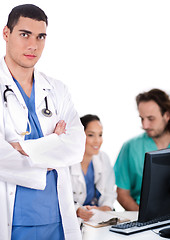 Image showing Serious young doctor looking at the camera, two others making notes in the background