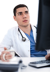 Image showing Young ethnic doctor looking deeply at the computer