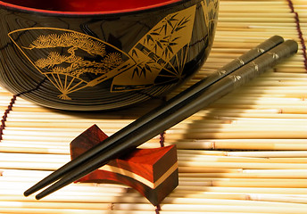 Image showing  Wooden bowl and chopsticks on a bamboo straws floor