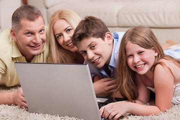 Image showing Domestic family lying in living room with lap top