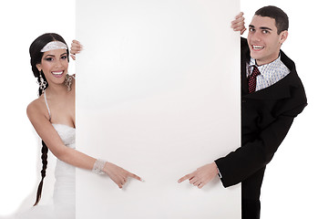 Image showing Bride and groom pointing at blank board